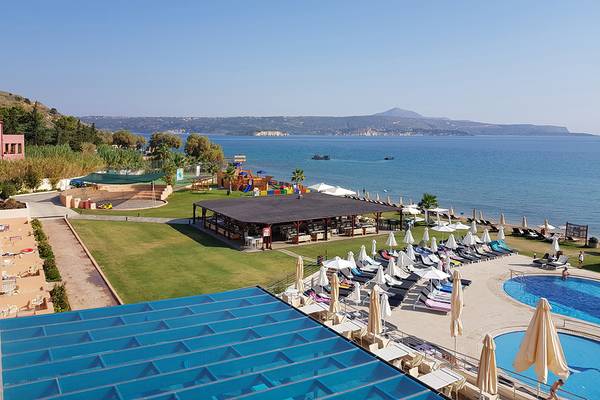 Luftaufnahme des Kiani Beach Resorts mit Swimmingpool, Liegestühlen und Spielplatz am Meer.
