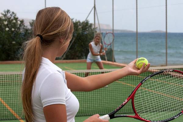 Tennisspielerinnen spielen auf einem Tennisplatz am Strand mit Blick auf das Meer.