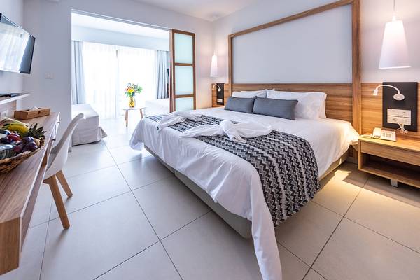 Hotelzimmer im Kiani Beach Resort mit einem Bett, Tisch und Früchtekorb.