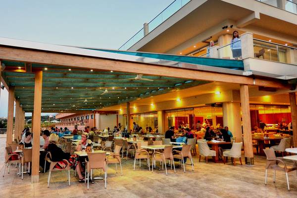 Menschen, die auf der Terrasse des Kiani Beach Resorts bei einem Abendessen sitzen.