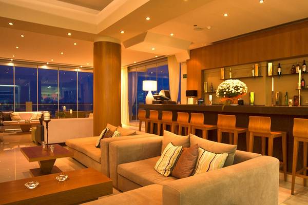 Loungebereich im Kiani Beach Resort mit Sofas, Tischen, Bar und Blick auf die Stadt.