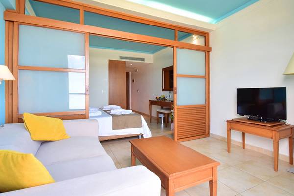 Suite-Zimmer im Kiani Beach Resort mit Wohnzimmer, Fernseher, Sofa, Tisch und Lampe.