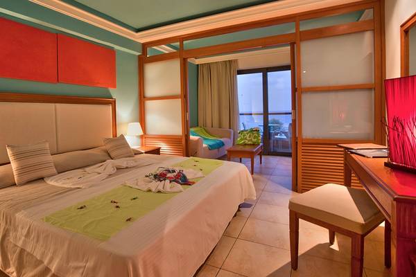 Ein Hotelzimmer im Kiani Beach Resort mit einem Bett, einem Schreibtisch und einer Terrasse.