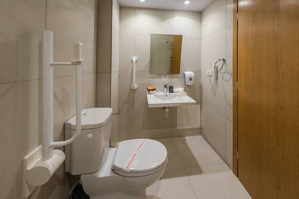 Behindertengerechte Toilette im Kiani Beach Resort mit Toilettensitz, Haltegriffen und Waschbecken.