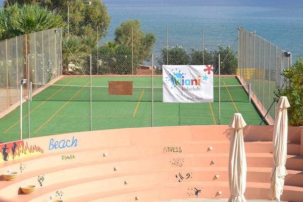 Tennisplatz im Kiani Beach Resort mit Blick auf das Meer, umgeben von bunten Wandmalereien und Sonnenschirmen.