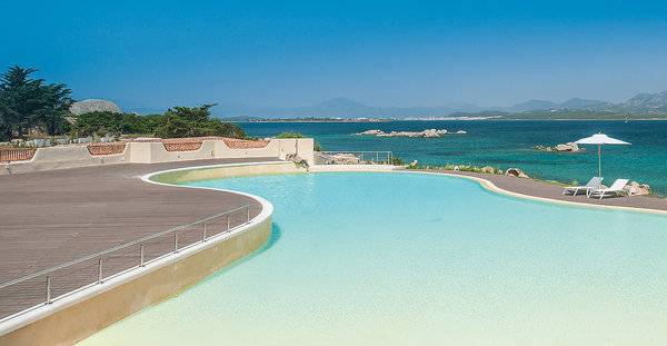Außenpool des Cala Cuncheddi Hotels mit Blick auf das Meer und Berge.