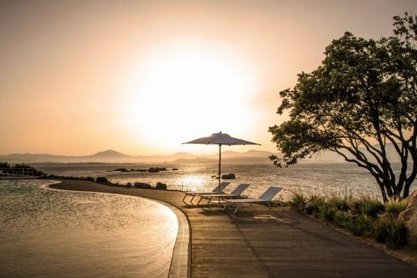 Sonnenuntergang am Cala Cuncheddi Hotel mit Strand, Lounges und einem Schirm
