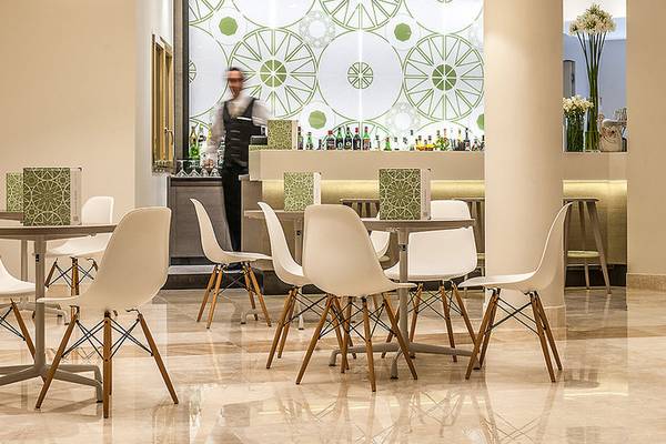 Cala Cuncheddi Hotellounge mit weißen Stühlen und runden grünen Wandmustern