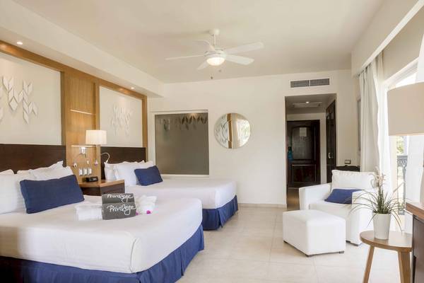 Zwei Betten im Schlafzimmer des Ocean Blue & Sand by H10 Hotels, mit Deckenventilator, Lampen und einem geräumigen Fenster.