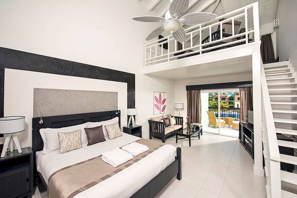 Innenansicht der Suite im Ocean Blue & Sand by H10 Hotel mit Bett, Couch, Deckenventilator und Poolblick.