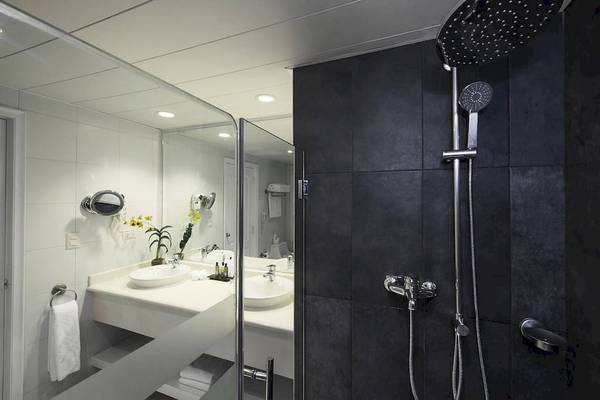 Badezimmer im Ocean Blue & Sand by H10 Hotel mit Dusche und zwei Waschbecken.