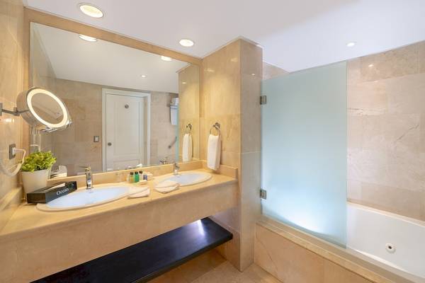 Badezimmer im Ocean Blue & Sand Hotel mit zwei Waschbecken, Spiegel und Badewanne.
