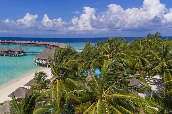 Luftaufnahme des Sun Siyam Vilu Reef Resorts mit vielen Bungalows und einem Swimmingpool.