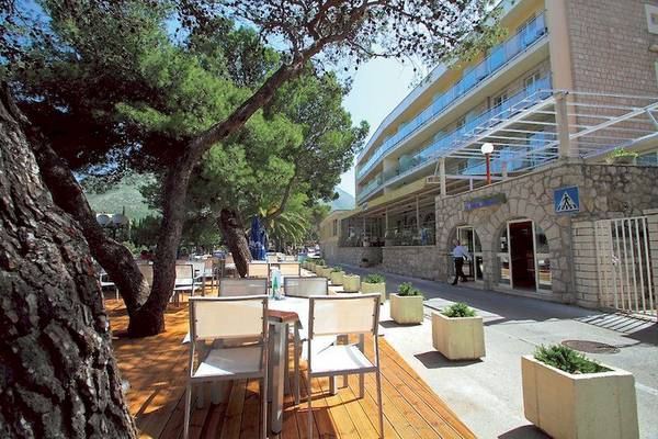 Außenbereich des Cavtat Hotels mit Terrasse, Tischen, Stühlen und Gehweg.
