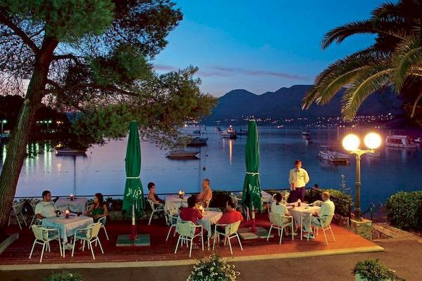 Terrasse des Cavtat Hotels bei Nacht mit Gästen und Blick auf den See und Berge