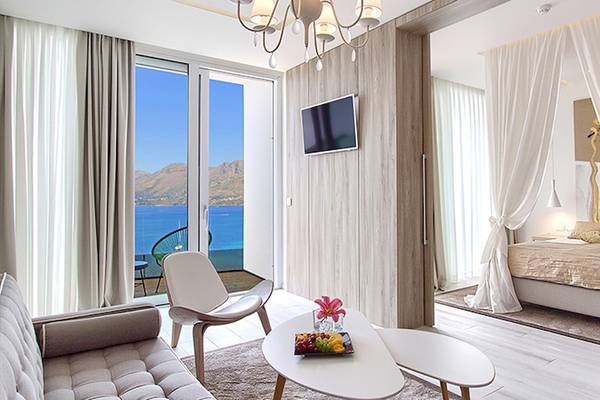 Suite-Zimmer im Cavtat Hotel mit Meerblick, modernes Interieur mit Bett, Fernseher, Tisch und Aussicht.