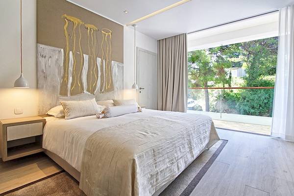 Schlafzimmer im Cavtat Hotel mit großem Bett und Ausblick auf die Natur.