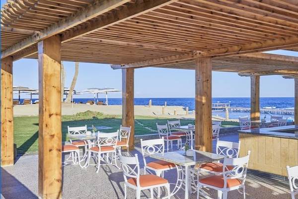 Außenbereich des Solymar Reef Marsa Hotel mit Tischen, Stühlen und Bar.