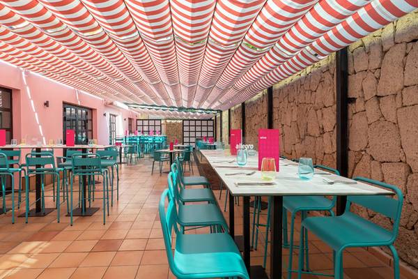 Innenansicht des Restaurants im Aparthotel Allegro Isora mit roten und weißen Sonnendach, blauen Stühlen und Tischen.