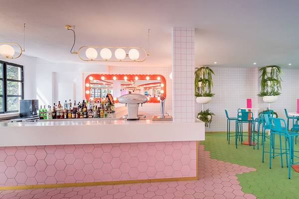 Innenansicht der Bar im Aparthotel Allegro Isora mit pinken und grünen Hexagon-Fliesen und blauen Stühlen.