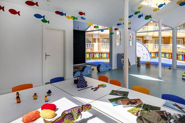 Ein farbenfrohes Kinderzimmer im Aparthotel Allegro Isora mit Spielzeug und Wanddekoration.