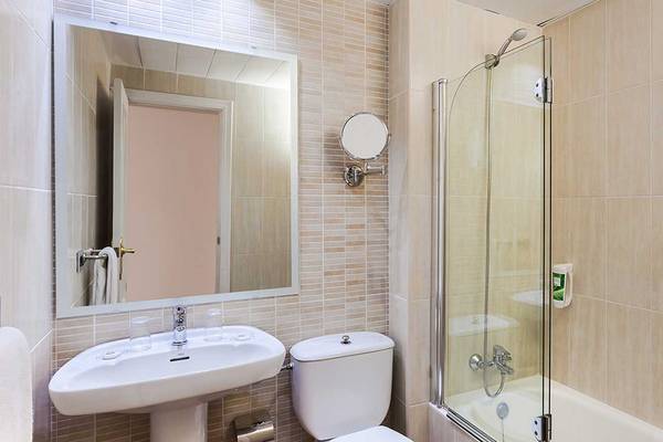 Badezimmer im Aparthotel Allegro Isora mit Badewanne, Toilette und Waschbecken.