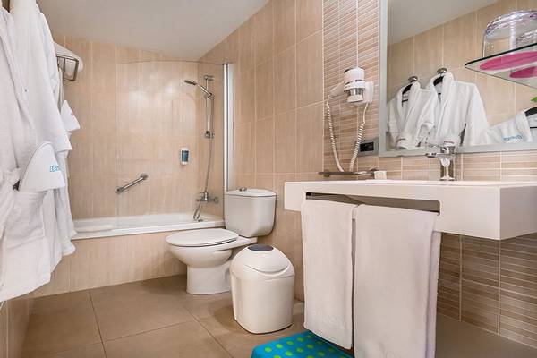 Badezimmer im Aparthotel Allegro Isora mit Dusche, Badewanne, Toilette, Waschbecken und Handtüchern