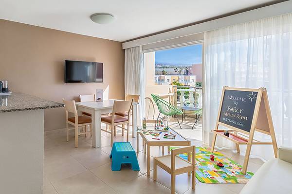 Innenansicht des Familienzimmers im Aparthotel Allegro Isora mit Esstisch, Fernseher und Balkon