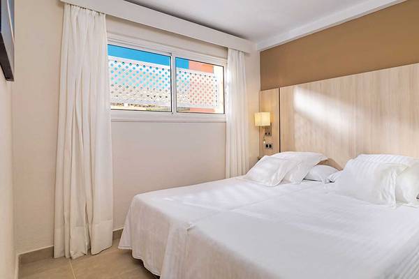 Doppelbettzimmer im Aparthotel Allegro Isora mit weißem Bettzeug und zwei Fenstern.