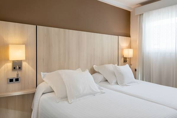 Doppelbett-Zimmer im Aparthotel Allegro Isora mit weißen Laken und Kissen.