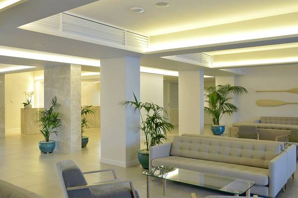 Lobby-Bereich des Sunrise Gardens Hotels mit gepolsterten Sofas, Tischen und Pflanzen in blauen Töpfen.