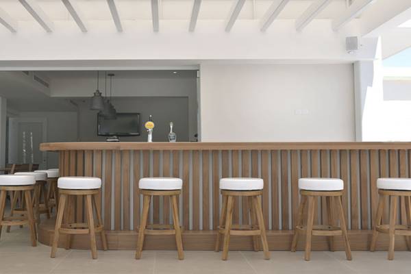 Ein modernes Hotelbar mit Holztheke und weißen Barhockern.