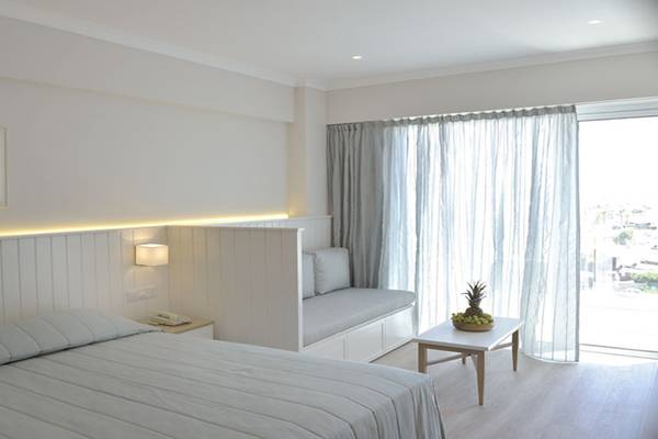 Ein Hotelzimmer im Sunrise Gardens mit weißem Bett, Leseecke und Aussichtsfenster.