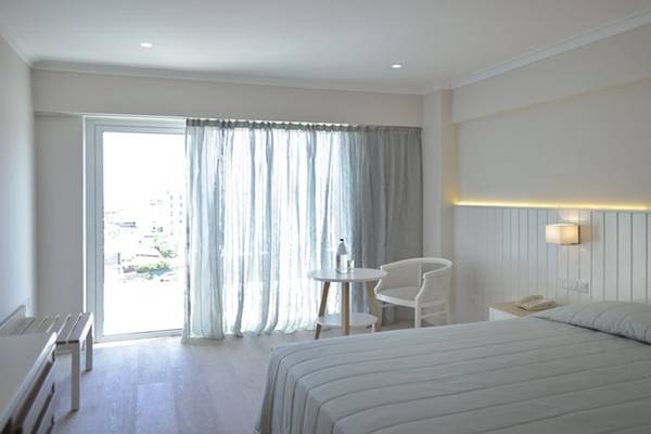 Ein elegantes Hotelzimmer mit Doppelbett, Tisch, Stuhl und einem großen Fenster.