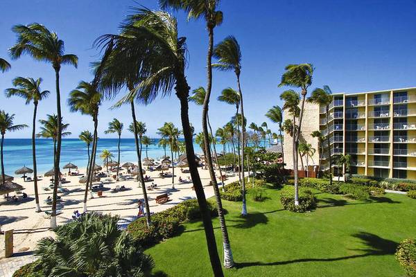 Außenansicht des Holiday Inn Resort Aruba mit Palmen und Strand im Hintergrund