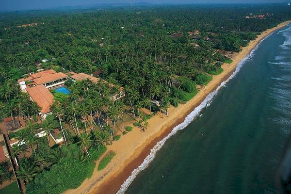 Luftaufnahme des Mermaid Hotel & Club mit Swimmingpool, umgeben von Palmen und einer Küste.