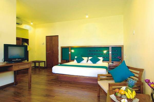 Schlafzimmer im Mermaid Hotel & Club mit Fernseher, Bett, Holzmöbeln und Obstkorb.