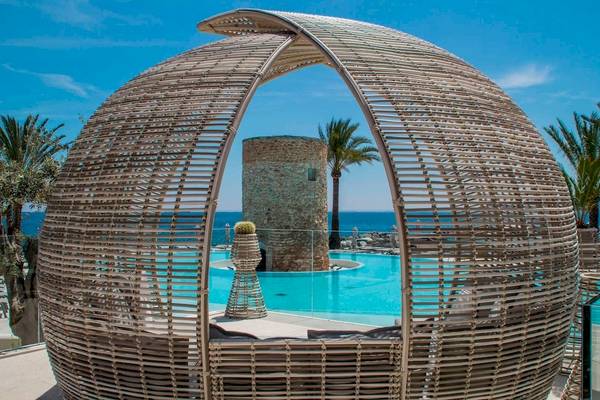 Loungebereich am Pool des Torre del Mar Hotels mit Blick auf das Meer und eine Steinsäule