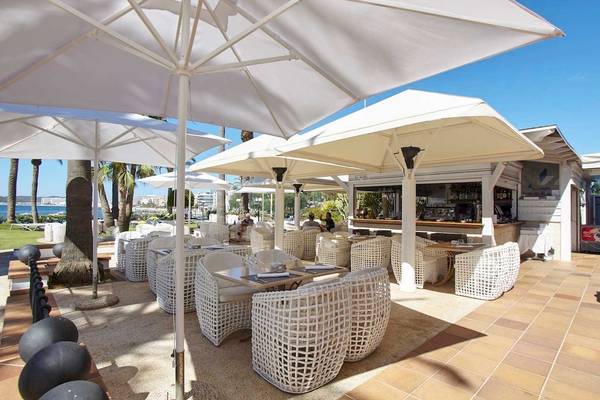 Außenterrasse des Torre del Mar Hotels mit weißen Sonnenschirmen und Tischen am Meer
