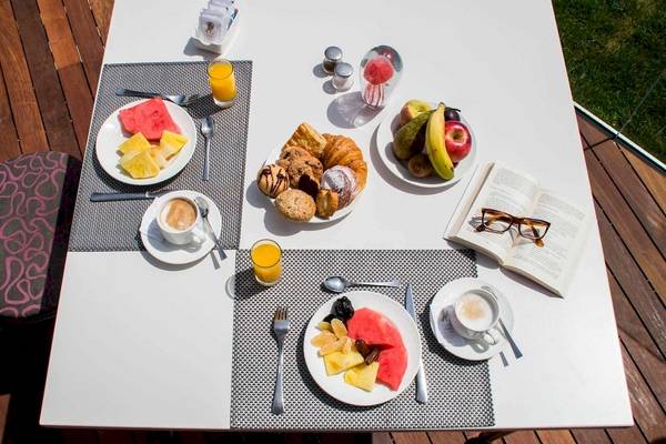 Frühstückstisch auf der Terrasse des Torre del Mar Hotels mit Früchten, Gebäck und Getränken.