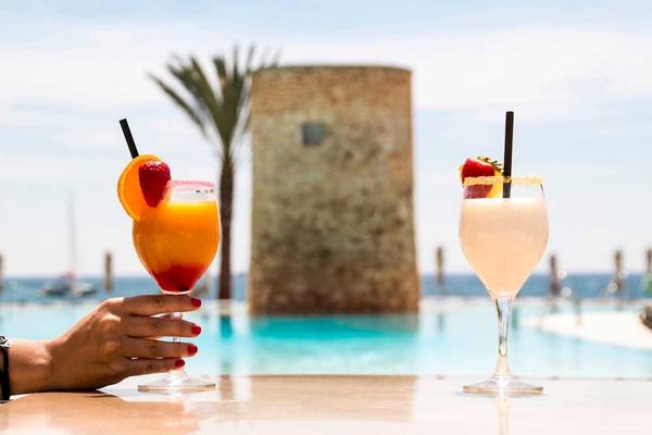 Hand hält Cocktails am Pool im Torre del Mar Hotel