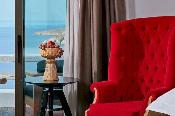 Zimmer im Myconian Avaton Resort mit Blick auf das Meer und roten Möbeln.