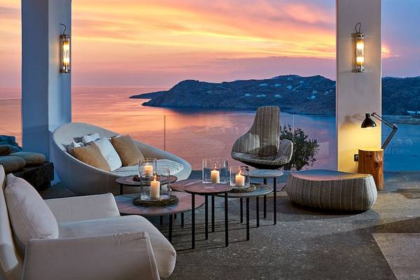 Terrasse des Myconian Avaton Resorts mit Ausblick auf den Meer, Stühle, Tische und Kerzen.