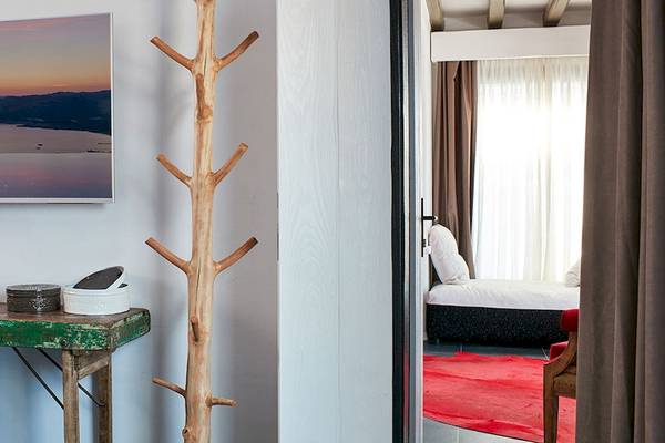 Innenansicht eines Zimmers im Myconian Avaton Resort mit Fernseher, Dekogegenständen und offenem Schlafzimmer.