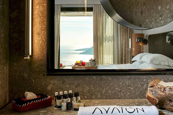 Blick aus dem Badezimmer des Myconian Avaton Resorts auf das Meer und das Bett