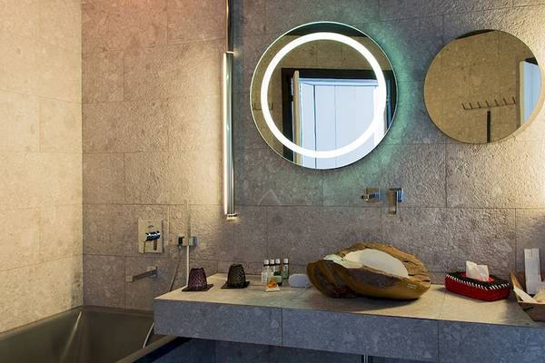 Badezimmer im Myconian Avaton Resort mit runden Spiegeln, Waschbecken und Badewanne.