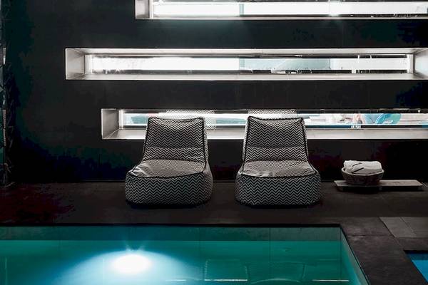 Pool-Lounge-Bereich im Myconian Avaton Resort mit zwei schwarzen und weißen Sesseln.