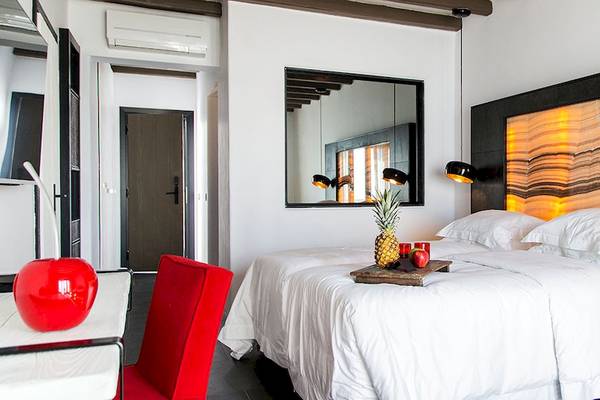 Schlafzimmer im Myconian Avaton Resort mit weißem Bett, Dekor und Früchten auf dem Bett