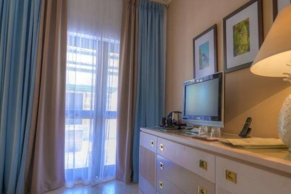 Innenansicht eines Hotelzimmers mit Fernseher, Lampen und Schreibwaren auf einem Sideboard.