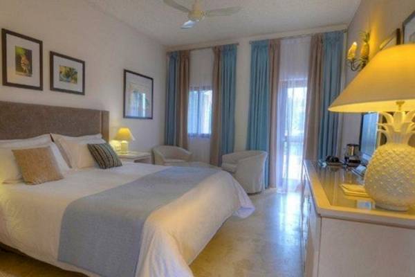 Hotelzimmer im Ta' Cenc & Spa mit großem Bett, Nachttischen, Lampen, Stühlen und einem Deckenventilator.